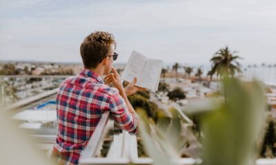 personal development - man reading book on balcony during daytim