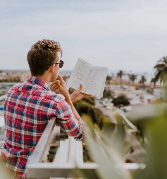 personal development - man reading book on balcony during daytim