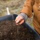 Soil Secrets - person in yellow jacket holding black soil